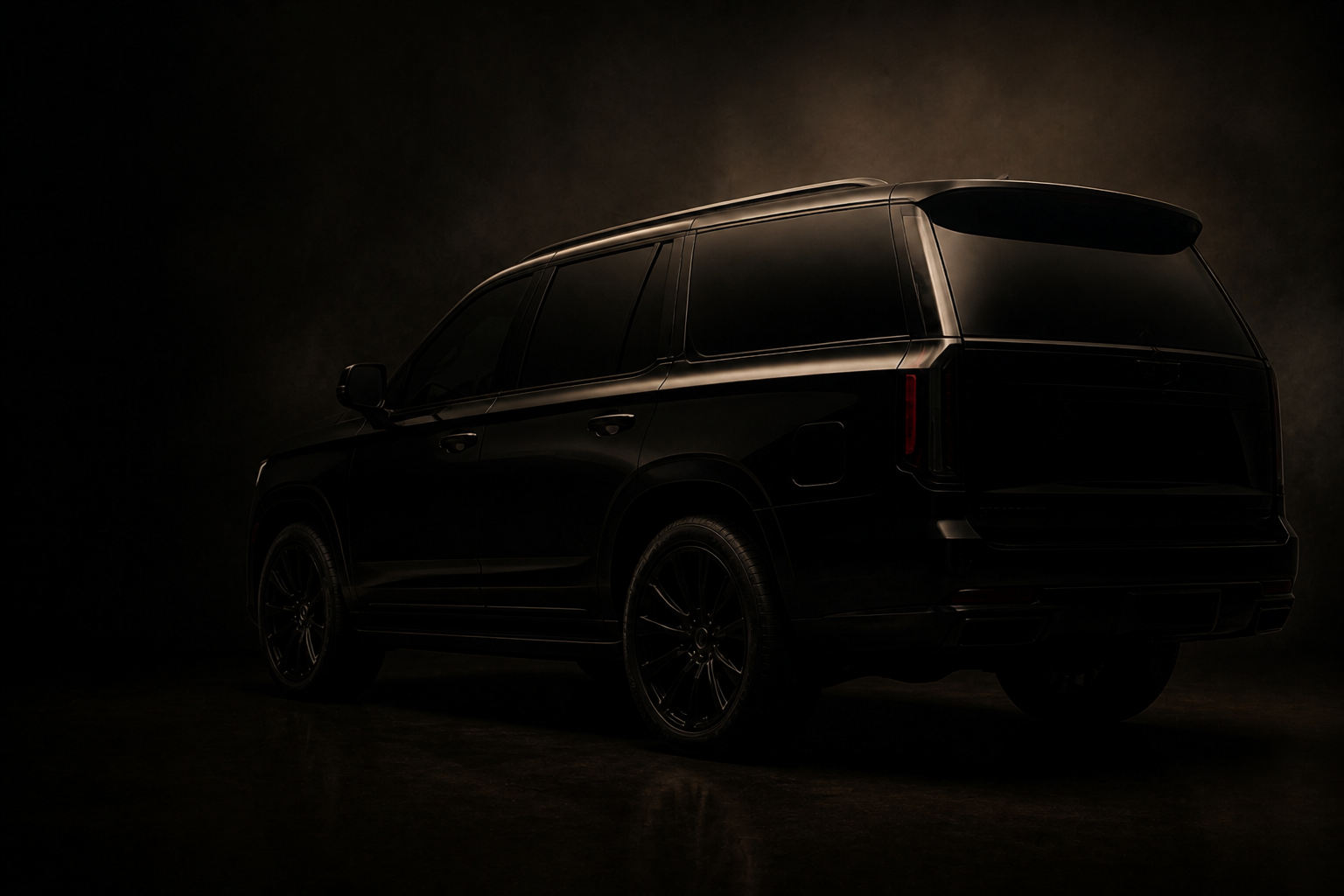 Dark full-size luxury SUV in a studio, rear three quarter view, tinted glass.