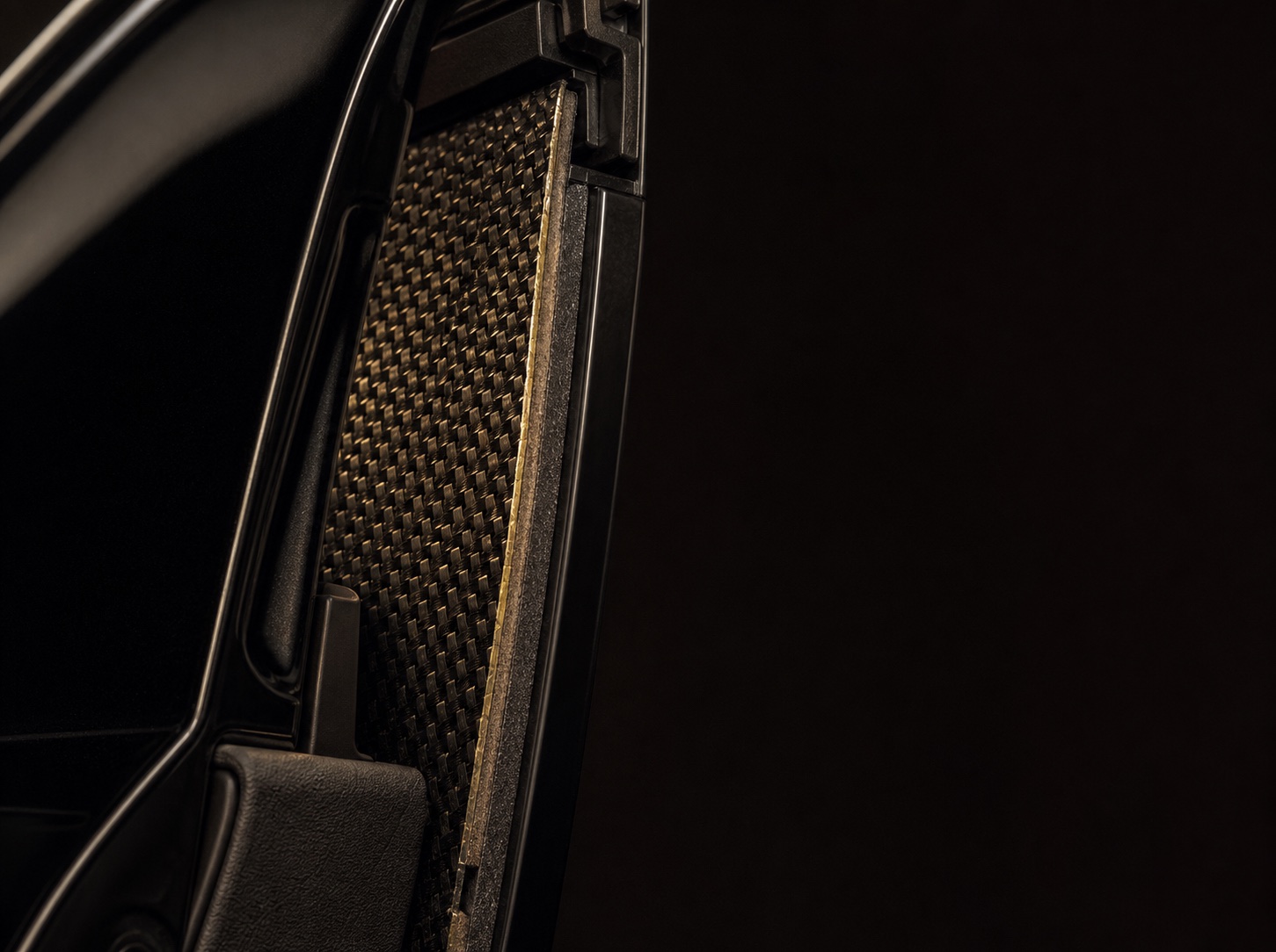 A woven aramid ballistic panel seen edge-on where it seats behind the door skin, the weave catching the light.